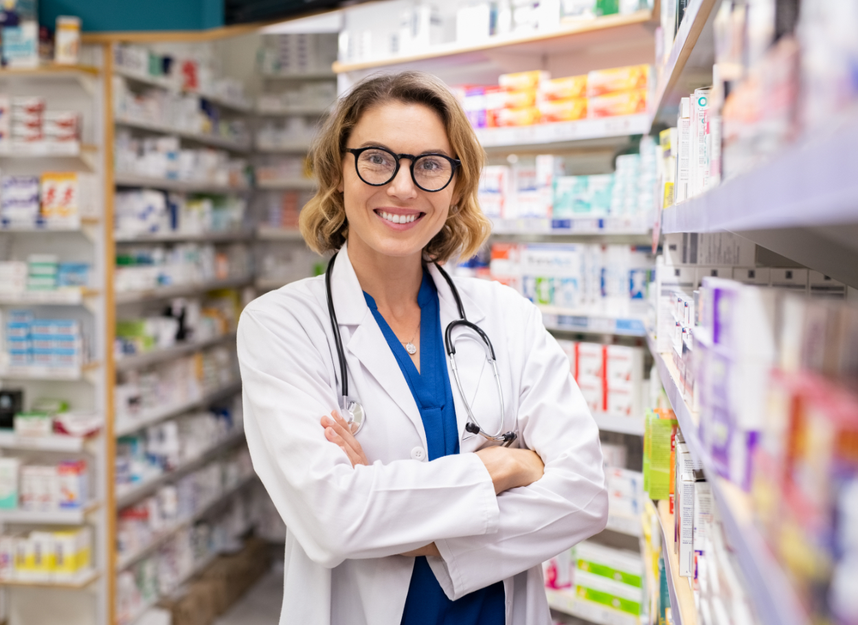 smiling female pharmacist standing in a pharmacy aisle